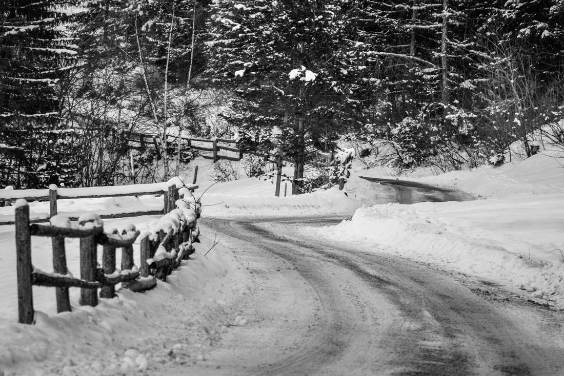 A snowy road beside a wooden fence